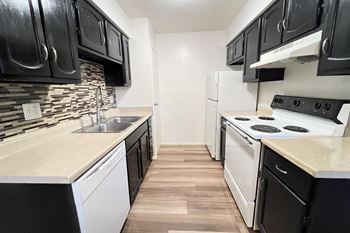 An empty kitchen with white appliances and black and white cabinets